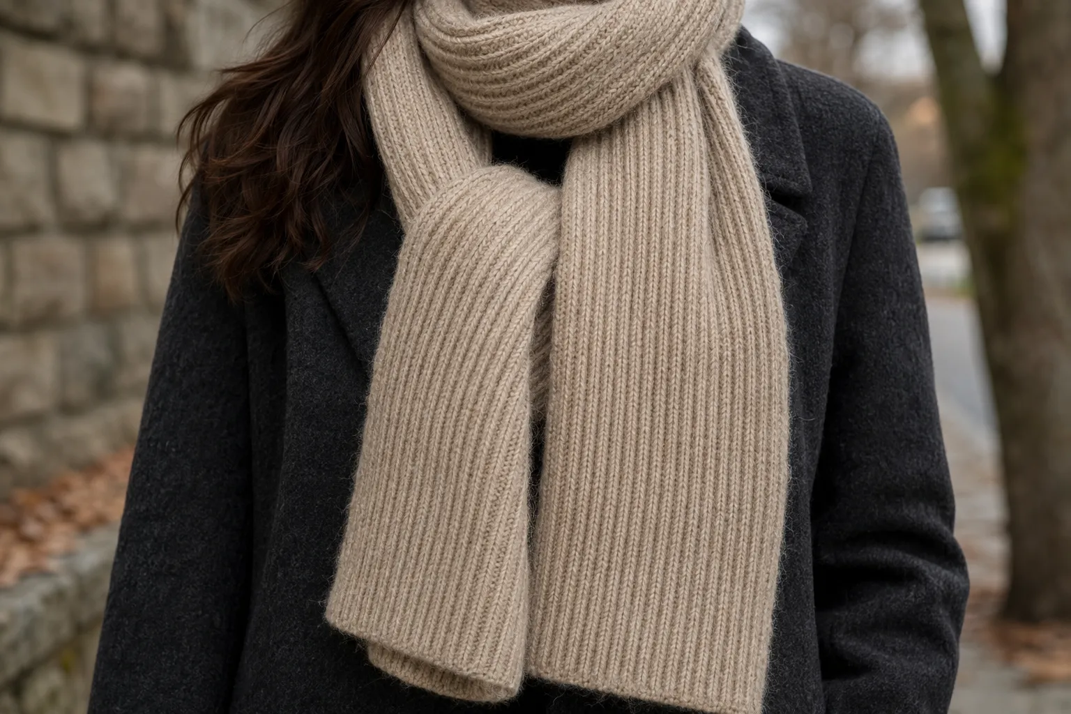 Adult wearing a long oatmeal rib-knit alpaca scarf over a charcoal coat